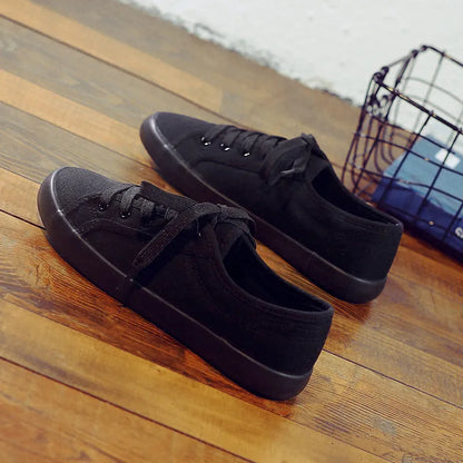 All-black women's canvas work shoes with flat rubber soles and lace-up front