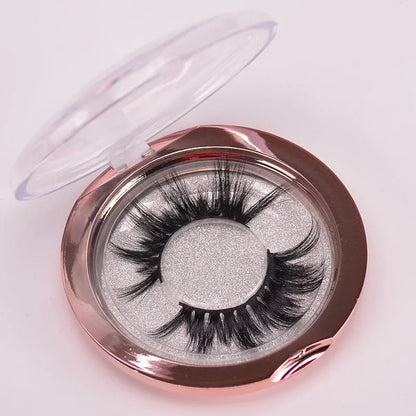 A pair of 5D mink false eyelashes with a hair storage cap and double-ended brush on a pink background.