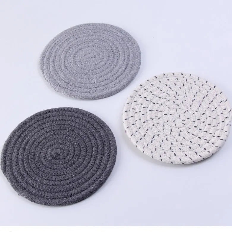Set of three round grey cotton cord coasters, each 18cm in diameter, on a wooden table.