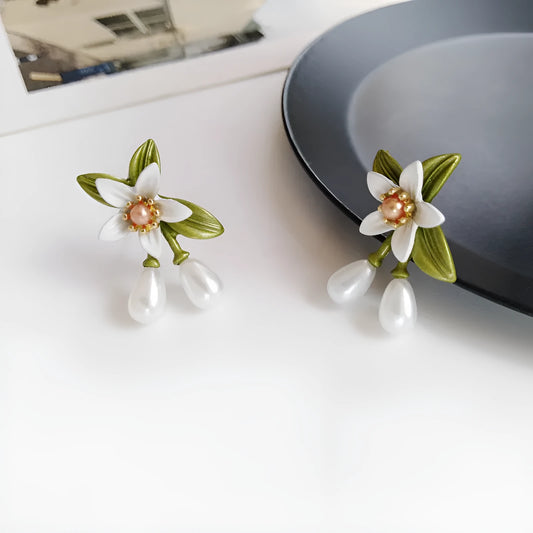 A pair of alloy flower ear studs and a pair of matching flower ear clips with a sterling silver needle detail.