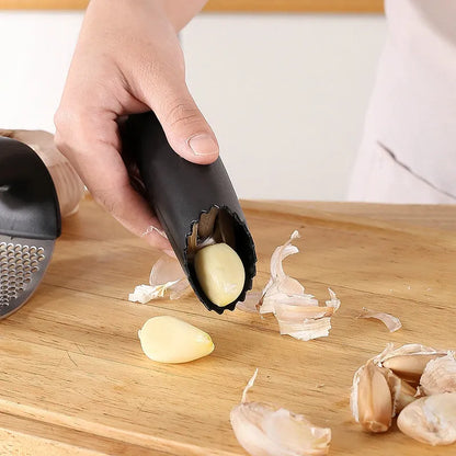 Stainless steel garlic press with coloured handles in a modern design, shown on a kitchen counter.