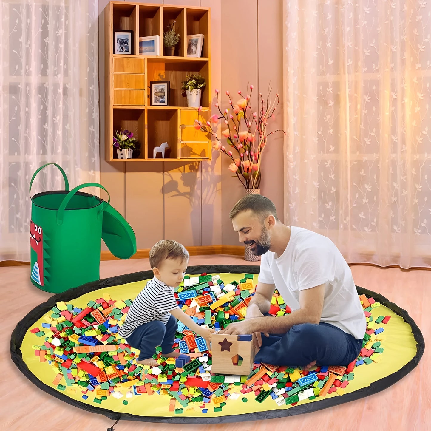 Green felt storage cube with pull rope unfolded into a large square play mat on a wooden floor.
