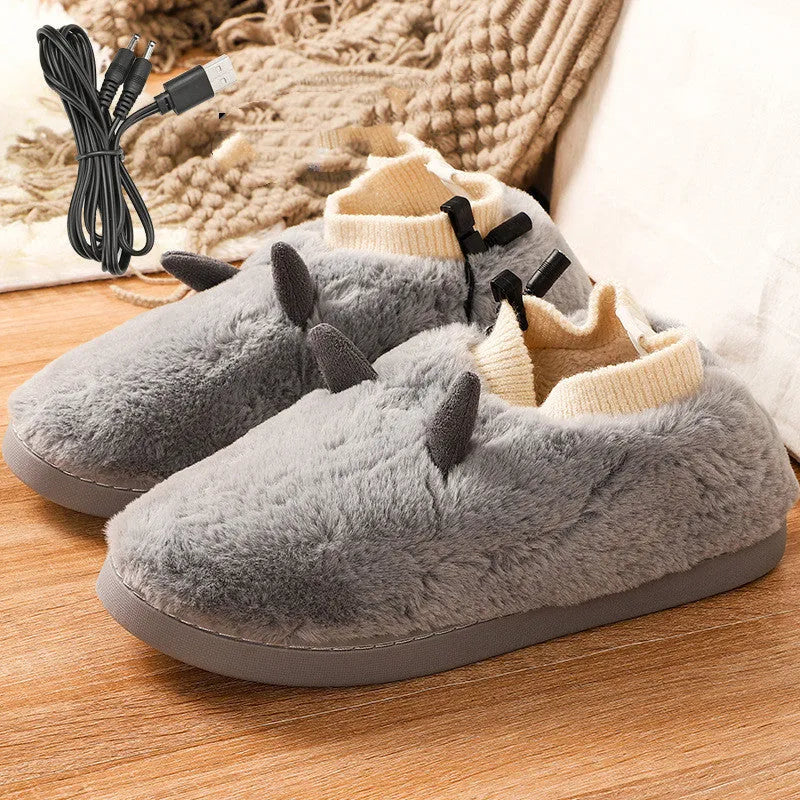 USB heated slippers in grey with a USB cable plugged into a power bank, showing the enclosed velvet design.