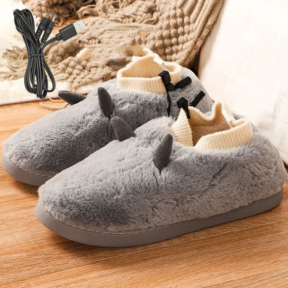 USB-powered electric slippers in black with a connected USB cable, showing soft velvet upper and plastic sole.