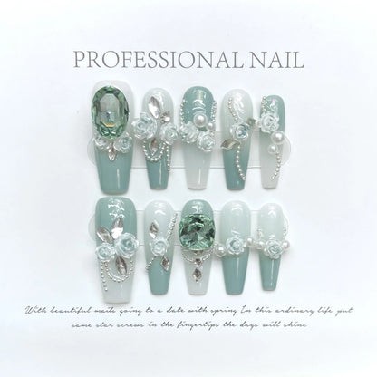 Wear Armor Green nail art set with pink camellia gradient crystal bows, butterflies, and chains arranged on a white plastic armour suit carrier.