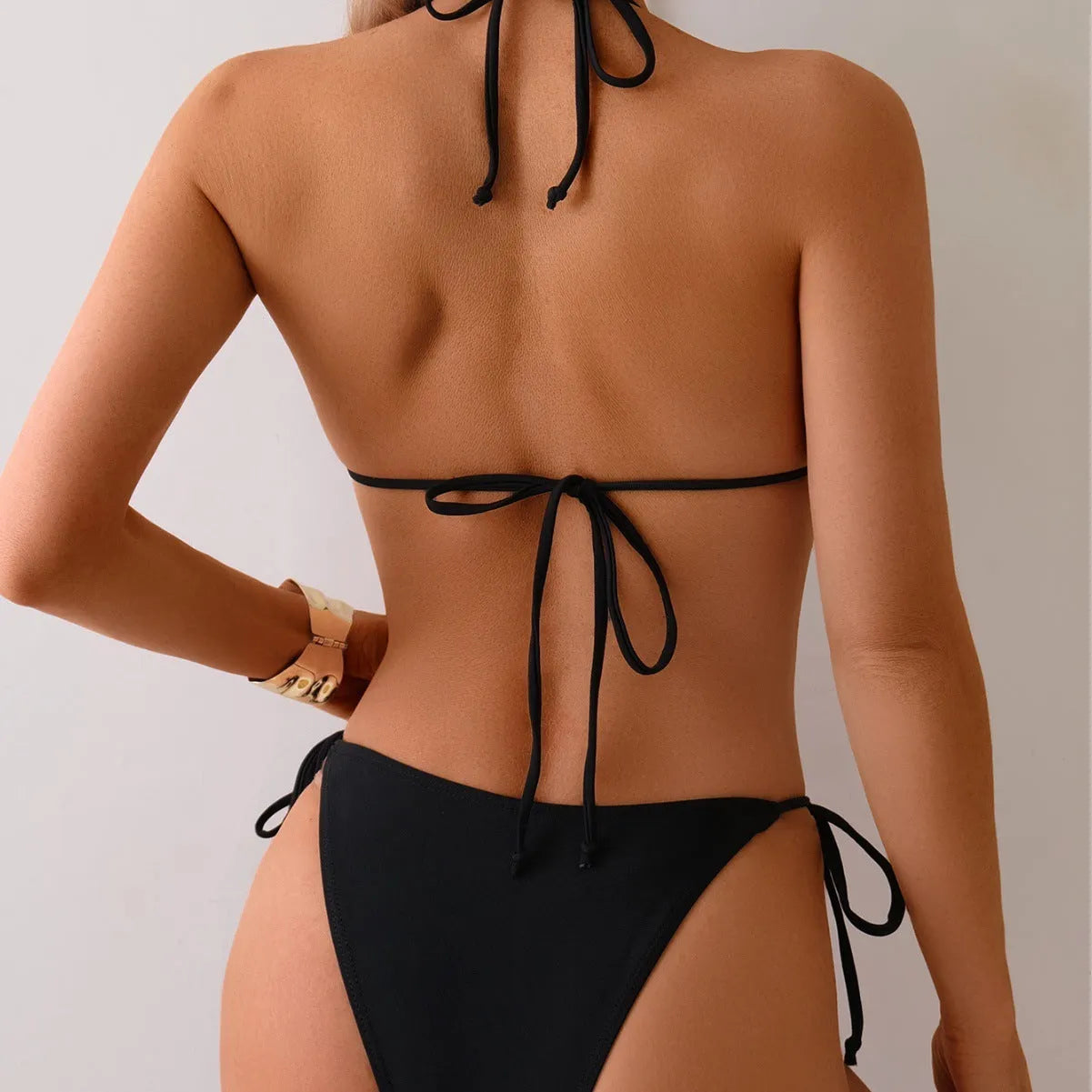 Black women's bikini swimsuit with metal bead detailing on split design, polyester construction
