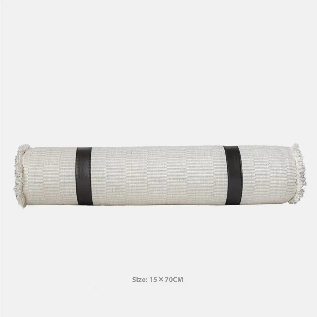 Grey and white plaid bed runner blanket with coordinating pillowcase and round leather pillow on bed