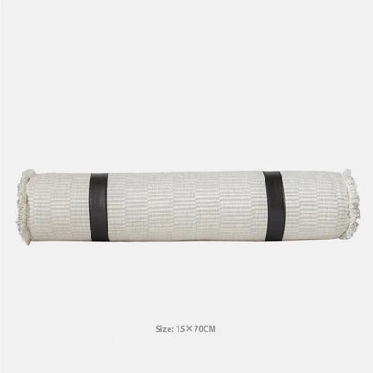Grey and white plaid bed runner blanket with coordinating pillowcase and round leather pillow on bed