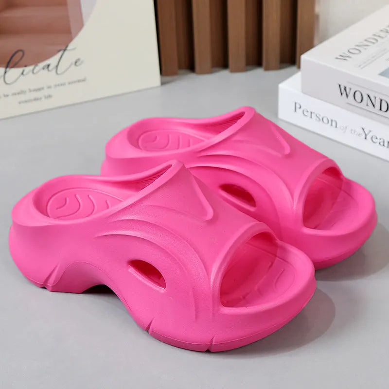 Women's thick-soled EVA foam beach slippers in rose red colour on a sandy background.