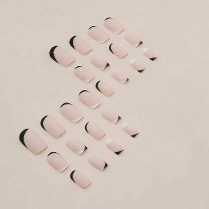Set of 24 black and white frosted French tip fake nails with matte finish, laid out in size order.