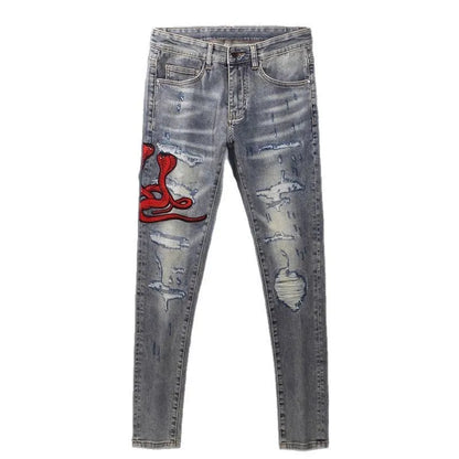 Men's slim fit blue jeans with washed-out finish, hole patches, and embroidery detail.