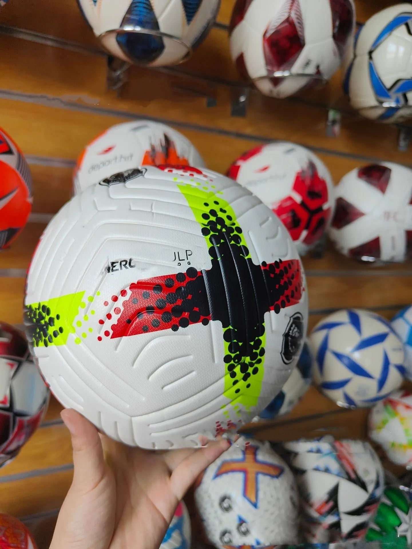 Fluorescent green Size 5 football with seamless patch construction on a green pitch.