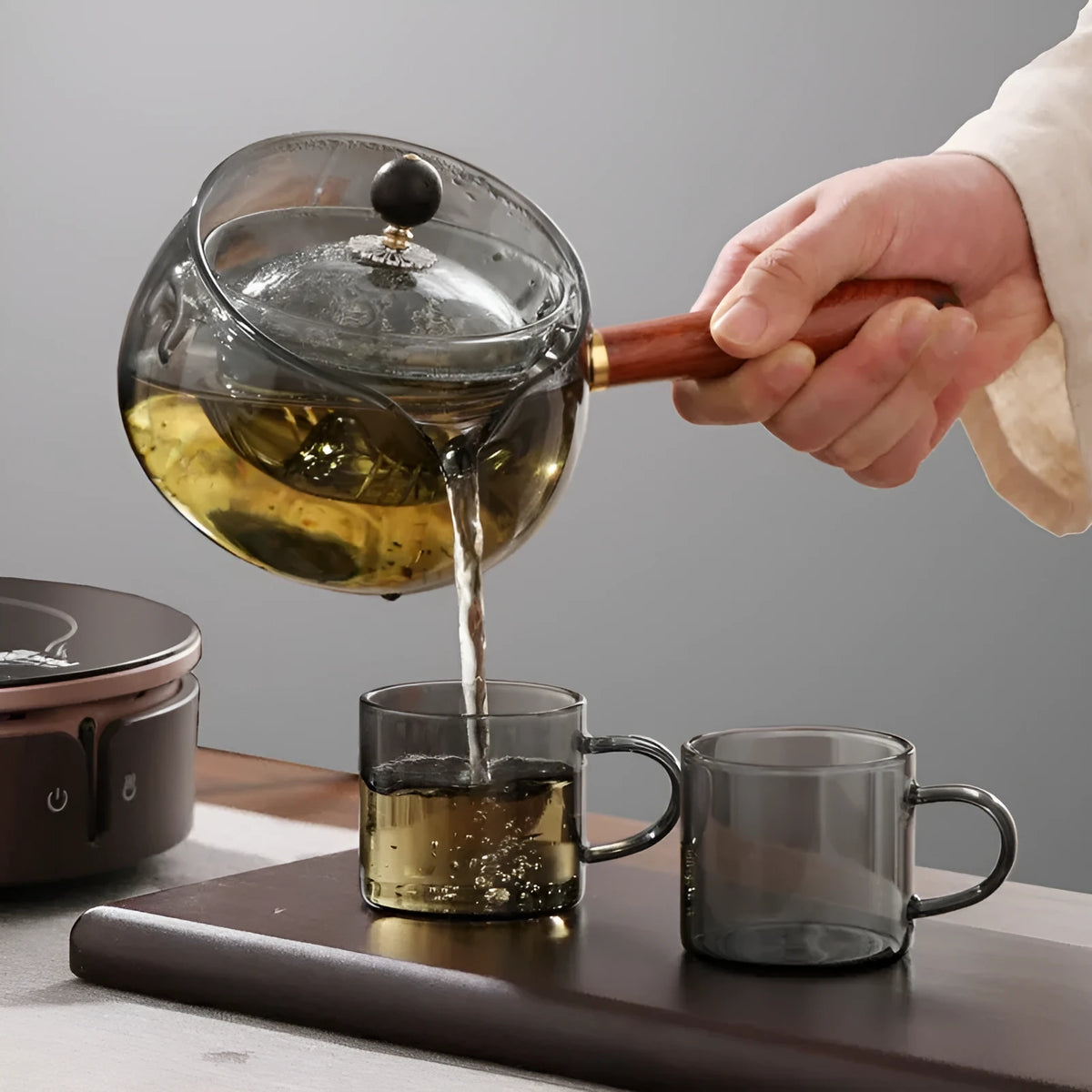 Glass teapot with wooden handle showing transparent borosilicate construction and removable infuser