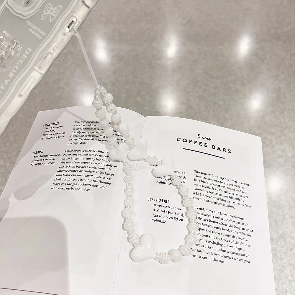 Transparent TPU iPhone case with 3D ice-through bow design on a mobile phone, showing optional white love lanyard attached.