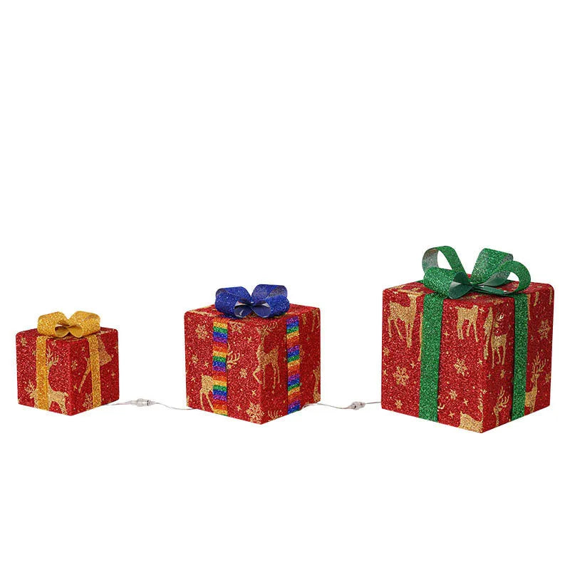 Set of three sparkling LED-lit Christmas gift boxes with red bows on a snowy porch.