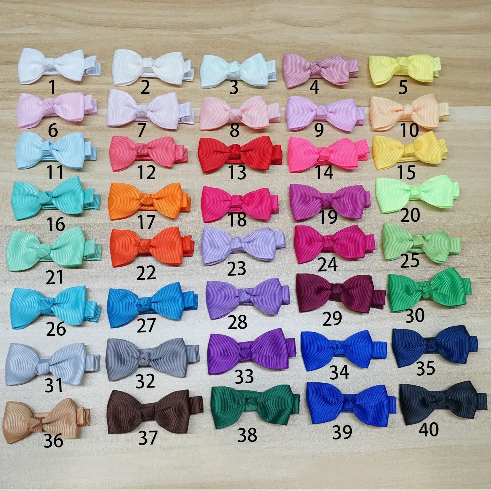 Assortment of pastel-coloured baby hair clips and bows arranged on a white background.