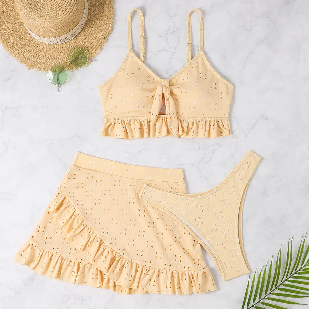 Women's white split hip skirt three-piece bikini swimsuit set on a mannequin.