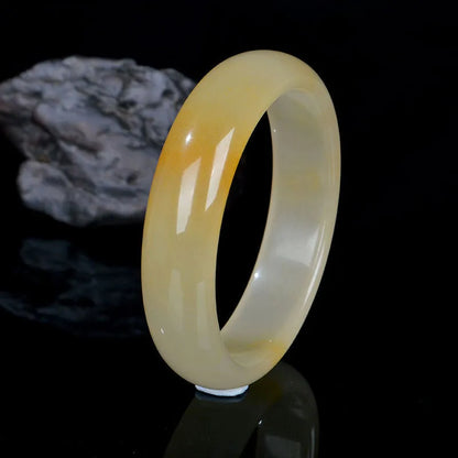 A polished natural light jade bracelet in a traditional Chinese style, shown on a wrist.