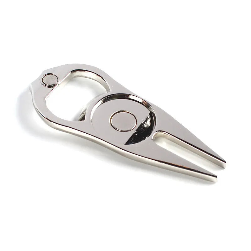 A black zinc alloy golf ball yoke tool with a bottle opener and a separate ball coin on a putting green.