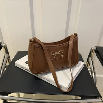 Western style shoulder bag with bow detail in rose pink colour, showing horizontal square shape and single strap.