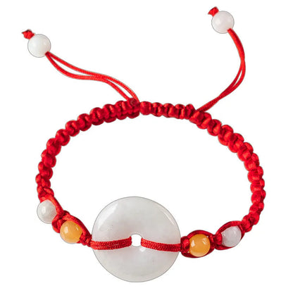 Round emerald green jade pendant on an adjustable red rope bracelet cord.
