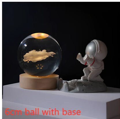 3D crystal ball night light projecting solar system pattern on wooden base with astronaut figurine