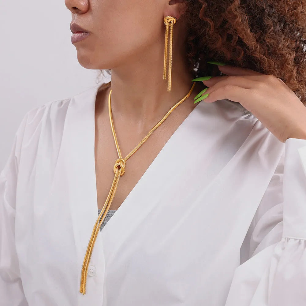 Gold electroplated titanium steel knotted tassel necklace and matching earrings set on a white background.