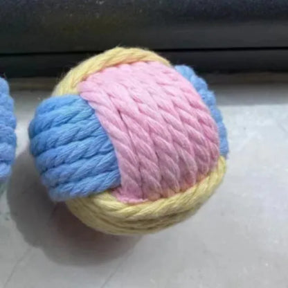 Handmade blue and pink plush cotton ball cat toy with textured surface on a wooden floor.