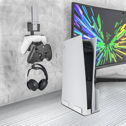A white wall-mounted plastic hook holding a black game controller and a TV remote.
