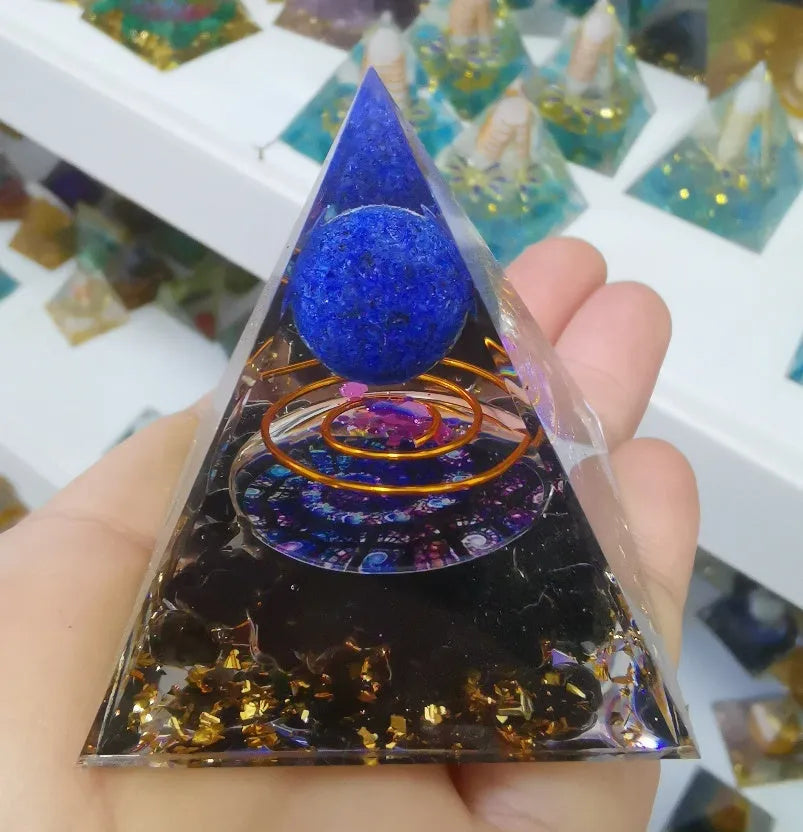 A small 6cm clear epoxy resin pyramid ornament containing pieces of natural crystal gravel on a flat surface.