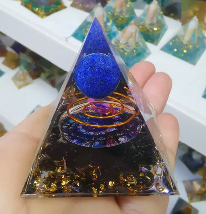 A small 6cm clear epoxy resin pyramid ornament containing pieces of natural crystal gravel on a flat surface.