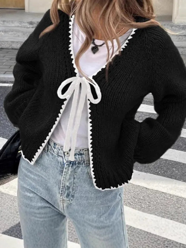 Loose grey lace-up front cardigan sweater with crocheted flower detail on a model.