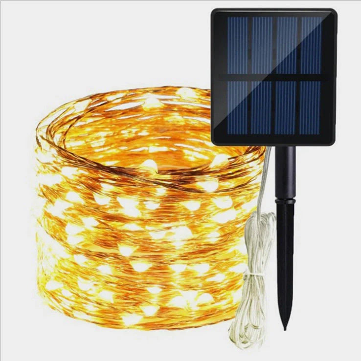 Solar-powered LED string lights arranged in garden with solar panel charging in sunlight