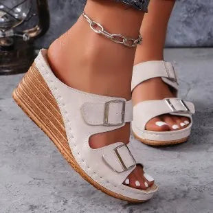 Women's creamy-white wedge slippers with an outer belt buckle and a rubber sole.