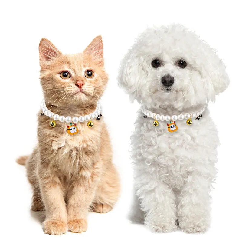 Three silver-tone pet necklaces with faux pearls and jingle bells laid flat on a surface.