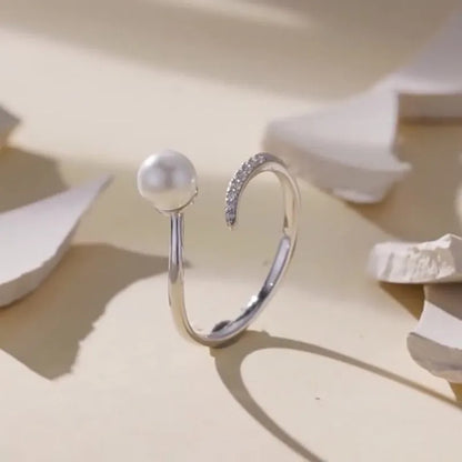 Silver adjustable open ring with white shell pearls on a white background.