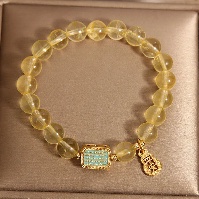 Women's bracelet made from yellow citrine crystal with rhinestone decoration on a white background.