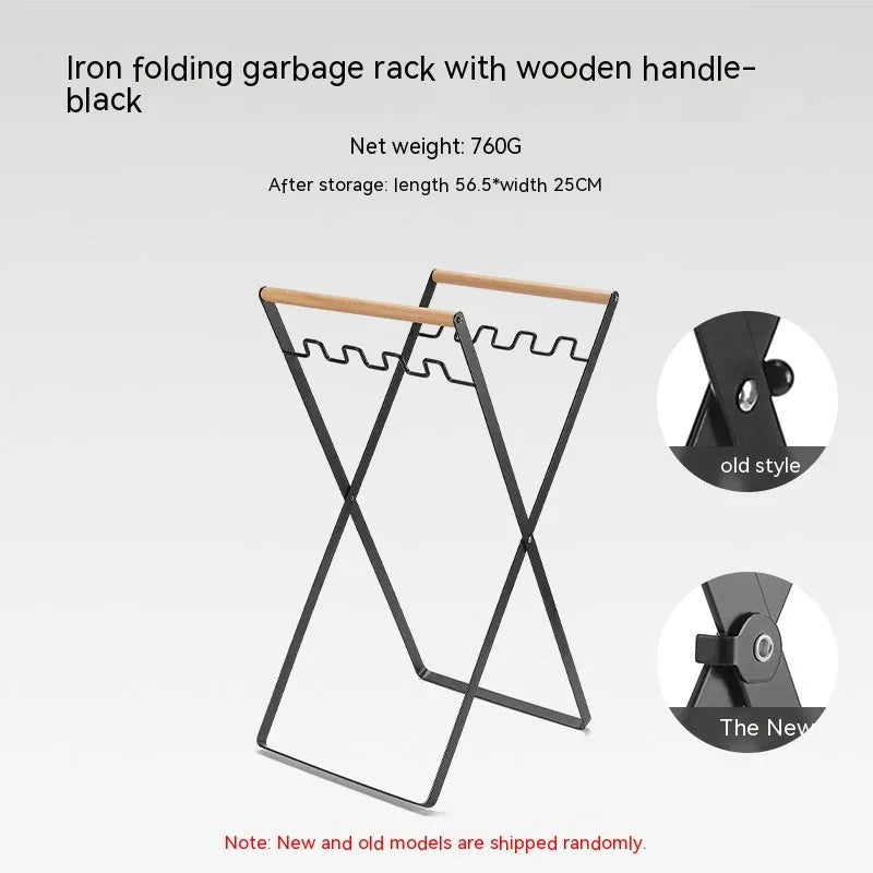 Black iron folding trash rack with wooden handles mounted on a wall holding a recycling bag.