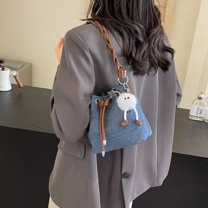 Blue synthetic leather cross body bucket bag with adjustable strap and optional hanging ornaments