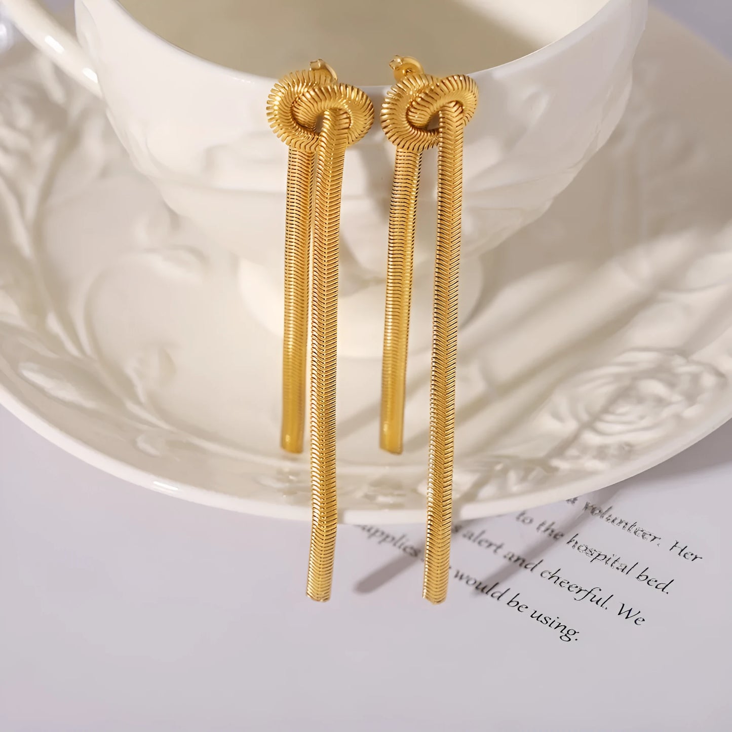 Gold electroplated titanium steel knotted tassel necklace and matching earrings set on a white background.