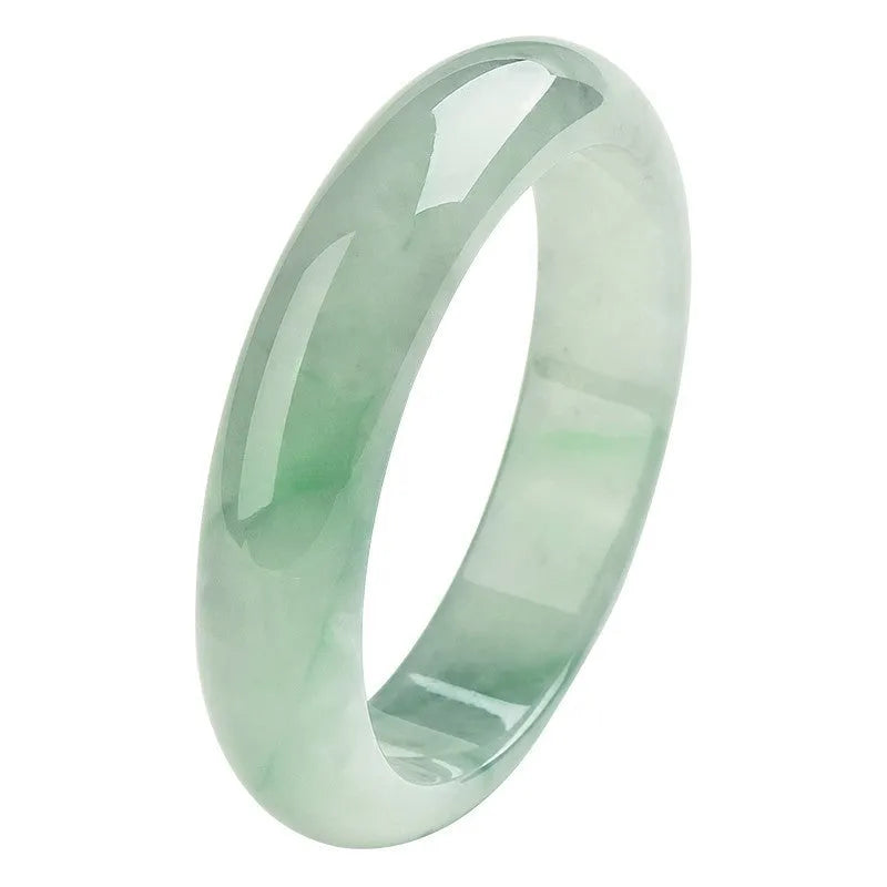 Light green solid jade bracelet on a wrist, showing its simple loop design and natural stone colour.