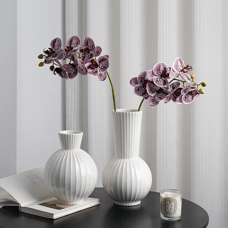 White ceramic ball-shaped vase with striped pattern, shown in small and large sizes with orchid arrangements