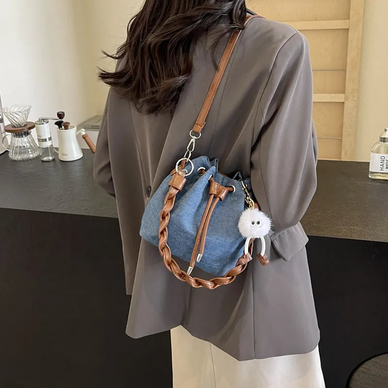 Blue synthetic leather cross body bucket bag with adjustable strap and optional hanging ornaments