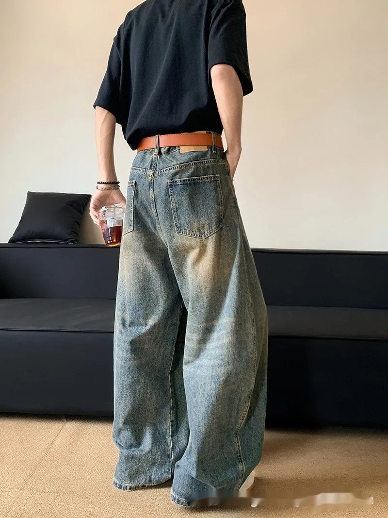 Man wearing retro blue distressed slim-fit jeans with a wide-leg cut.