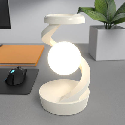 A rotating moon-shaped desk lamp with a wireless charging pad for smartphones, featuring a sleek and modern design.