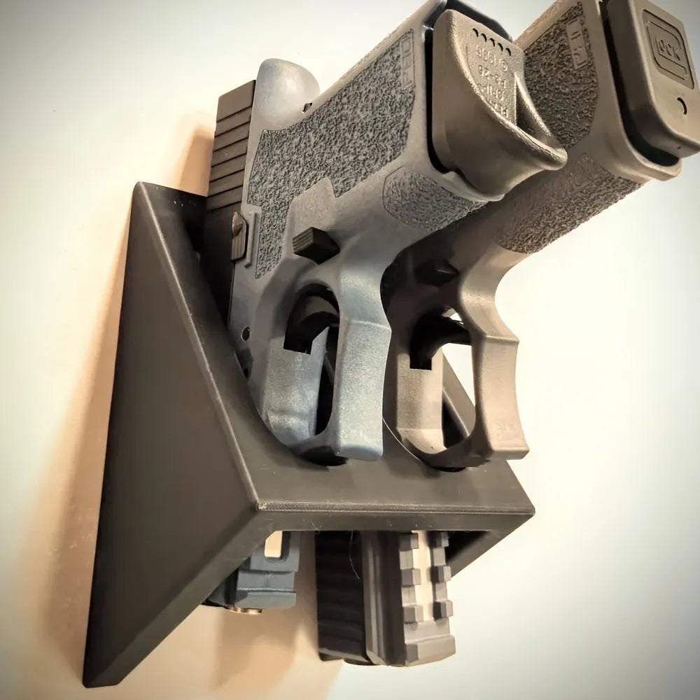 Black pistol-shaped plastic stand for displaying action figures or model collectables on a shelf.