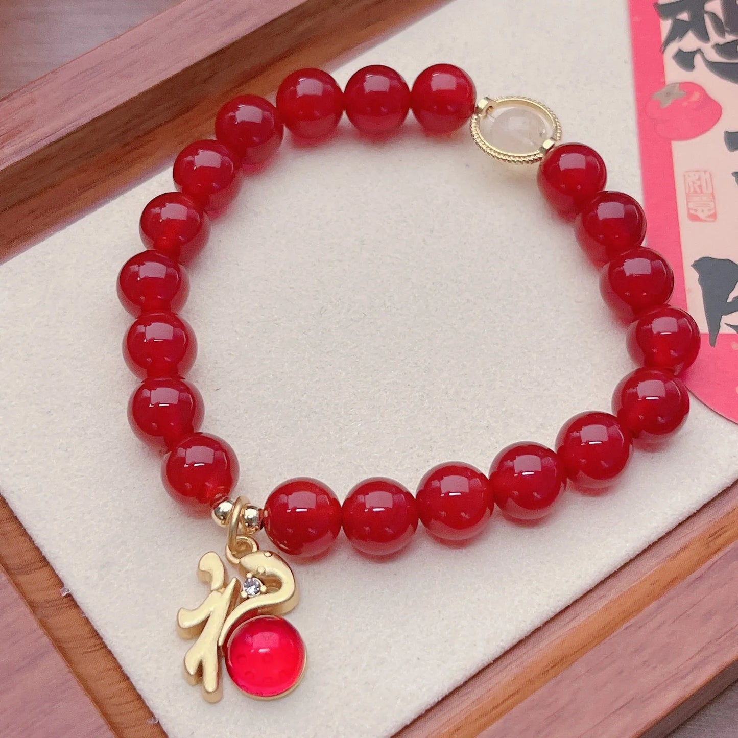 Close-up of a red agate bracelet featuring a detailed dragon design in a Chinese style.