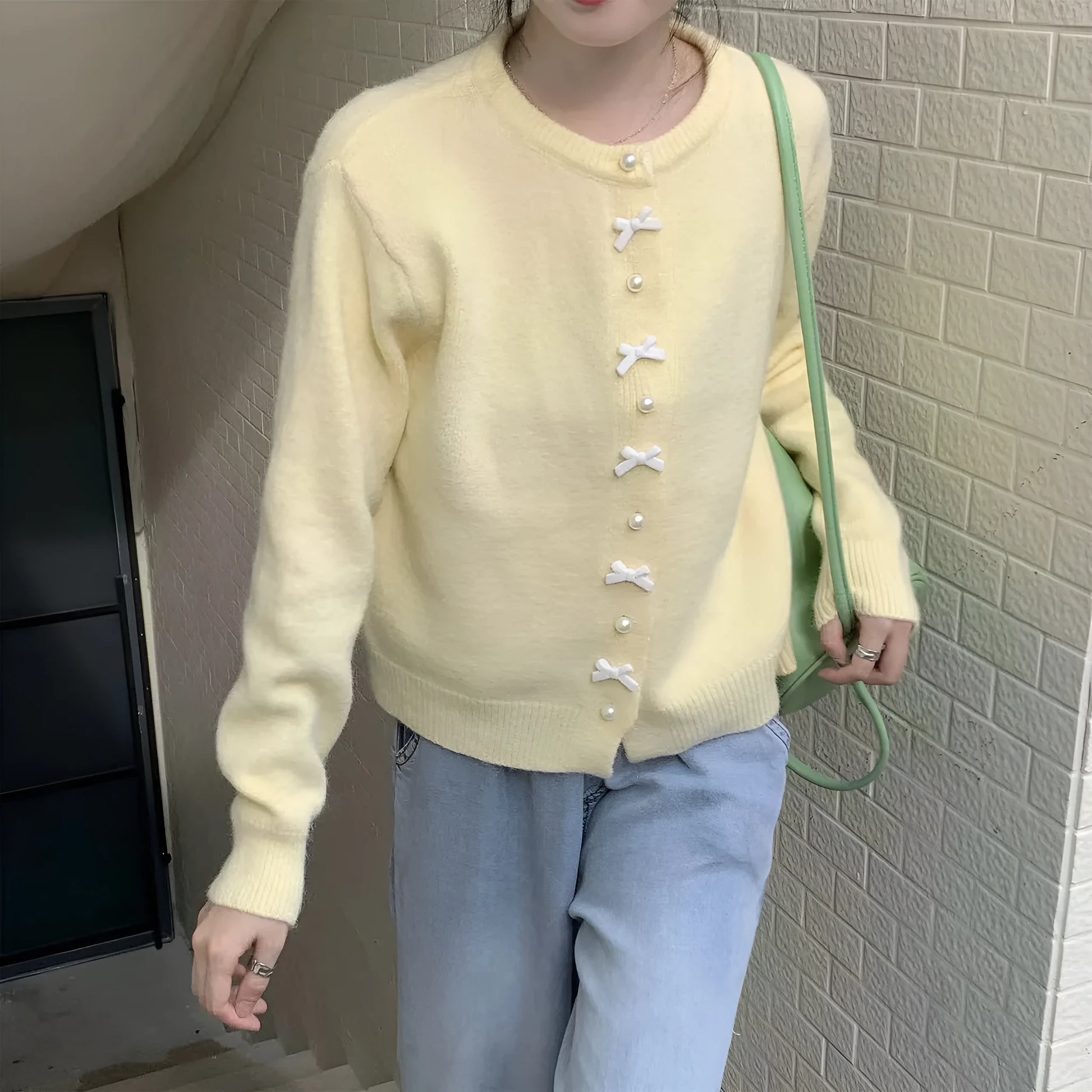 Women's solid colour cardigan sweater with bow pattern and pearl buttons in light blue.