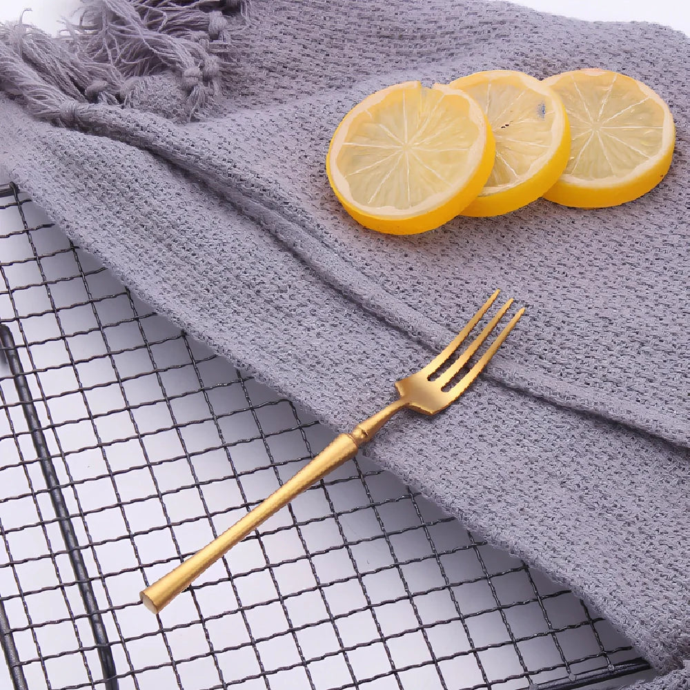 Four-piece stainless steel cutlery set showing main knife, fork, spoon, and teaspoon with mirror finish