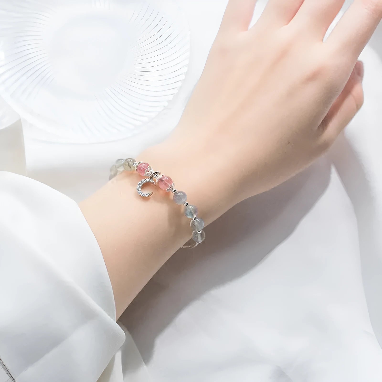 Natural moonlight-coloured moonstone bracelet with silver crescent moon charm on adjustable chain.